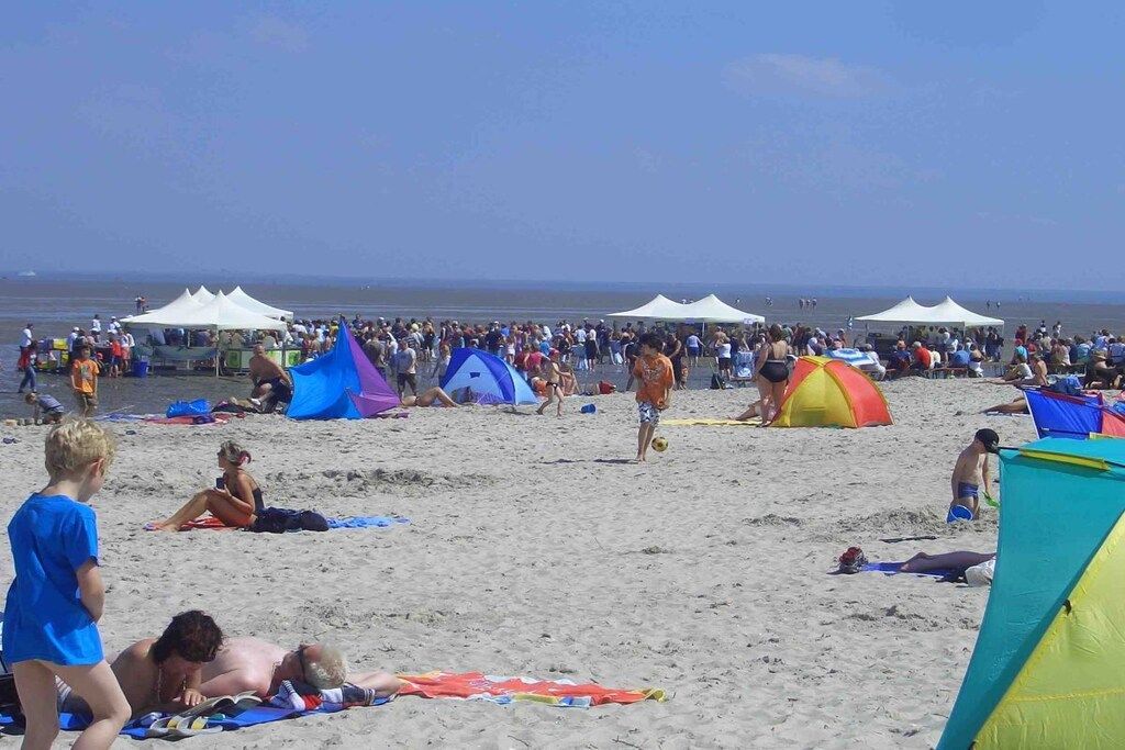 Ein voller Strand mit Zelten und Menschen.