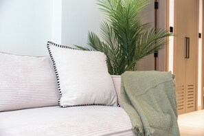 A sofa with striped cushions and a green throw blanket. - StayShort - Peace and Tranquility in this 1 Bedroom in JVC (Dubai)