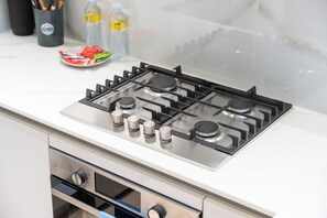 A kitchen with a stainless steel gas stove, a microwave, and a built-in oven. - StayShort - Peace and Tranquility in this 1 Bedroom in JVC (Dubai)