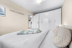 A bedroom with a bed, a wardrobe, and a door leading to a bathroom. - Dünenblick – Arrive. Breathe. See the Sea. Feel the Holiday. (Schönberg (Holstein))