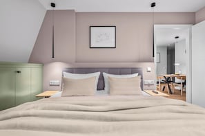A modern bedroom with a bed, bedside tables, a green wardrobe, and a dining area with a table and chairs. - Haus Elisabeth, Apartment 2, on the beach, with an underground parking space, Wi-Fi, and a balcony (Sylt)