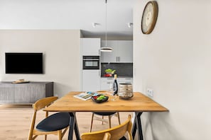 Una cucina moderna con zona pranzo, TV a schermo piatto e orologio a parete.