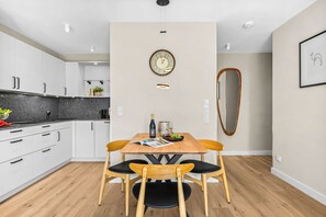 Eine moderne Küche mit weißen Schränken, einem Holzespeisetisch und einer großen Wanduhr.