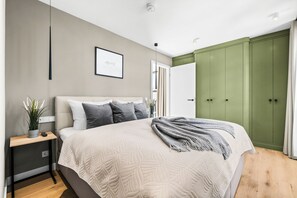 Una camera da letto moderna con un letto grande, un comodino, un armadio verde e un quadro appeso al muro.