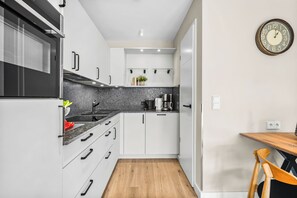 Una cucina compatta con mobili bianchi, un piano di lavoro in granito e un tavolo da pranzo in legno.