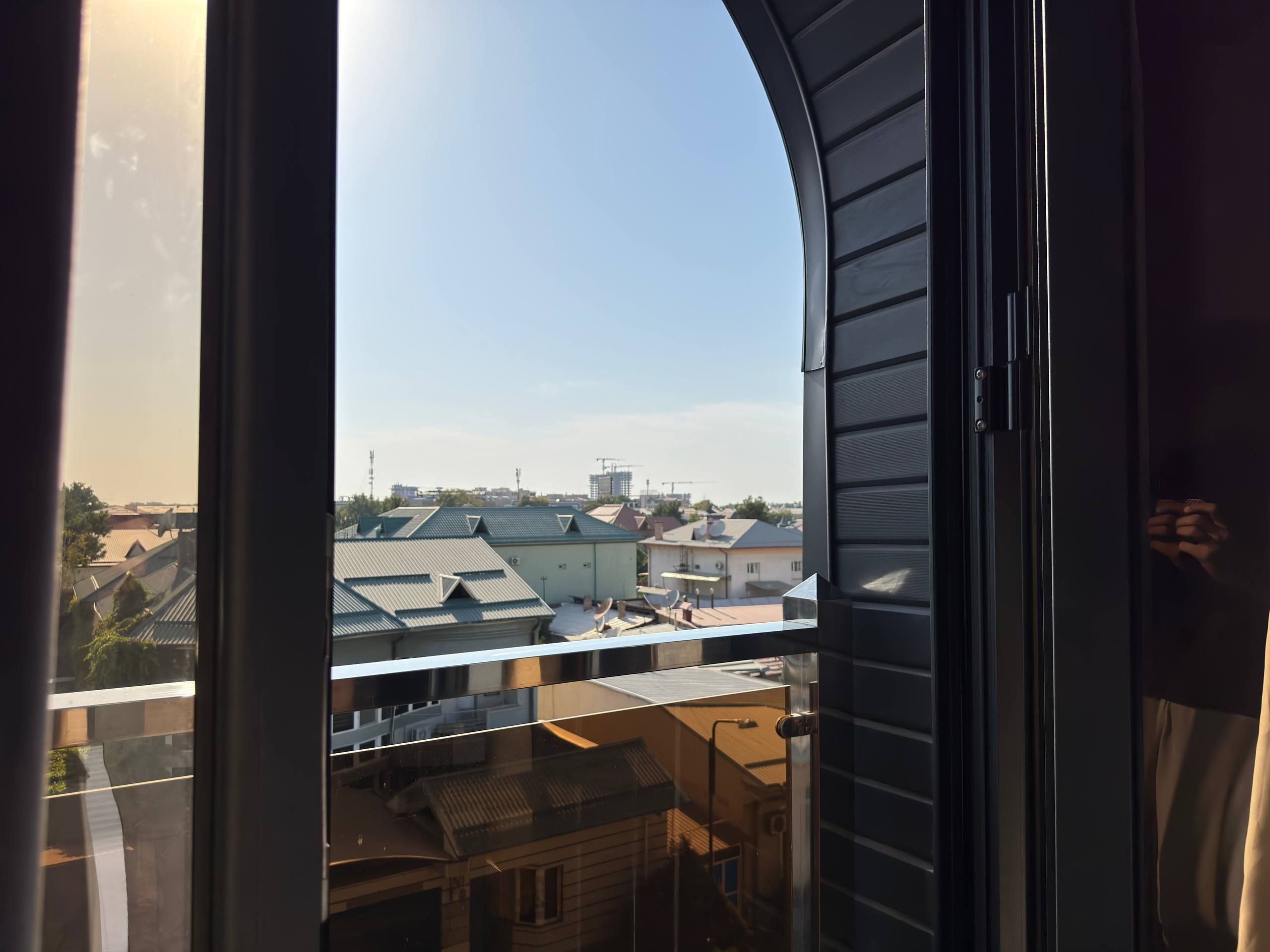 Vista a través de una ventana con marco curvo, que da a una zona residencial con casas y tejados.