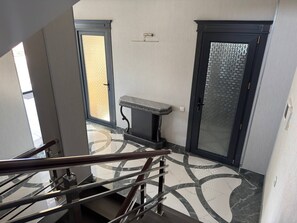Un interior moderno con piso de mármol, un banco y una puerta con panel de vidrio texturizado.