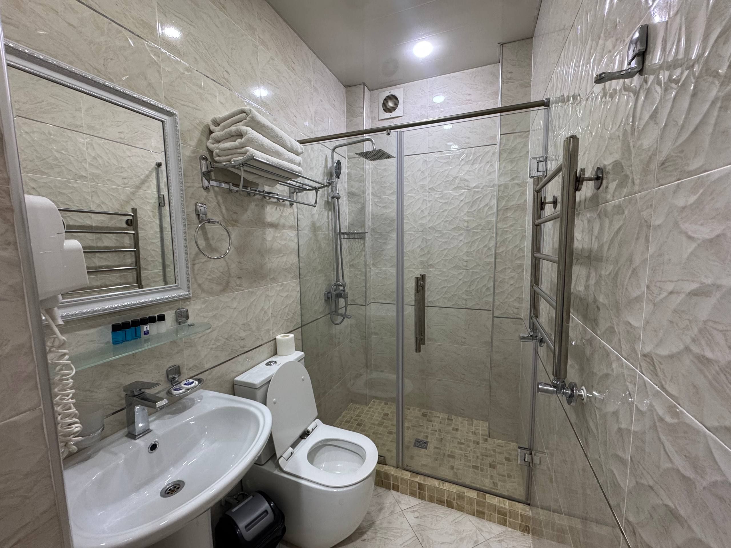 Un baño moderno con ducha de vidrio, lavamanos e inodoro.