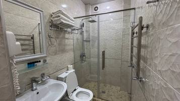 Un baño moderno con ducha de vidrio, lavamanos e inodoro.
