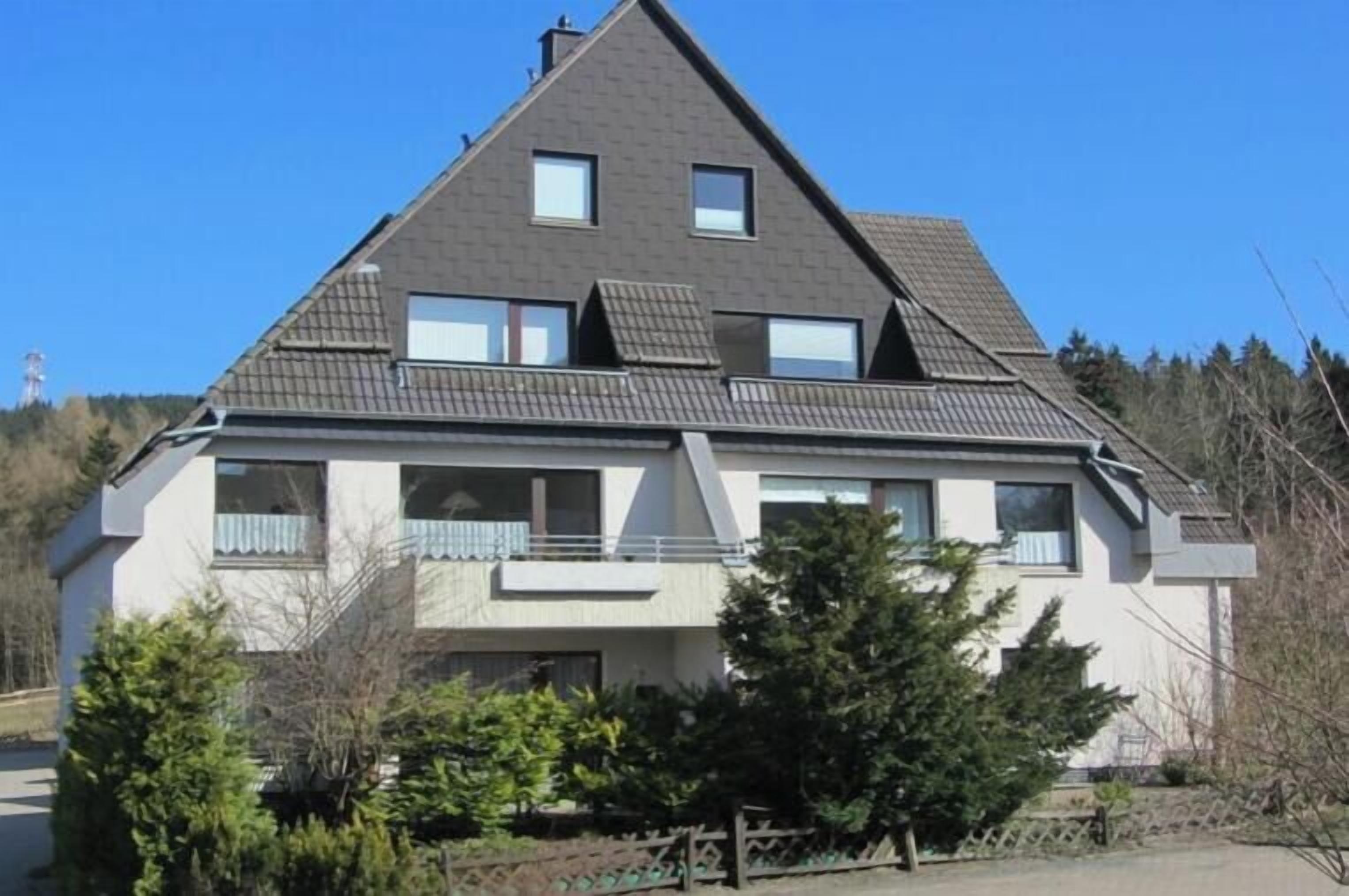 A two-story residential building with a sloped roof, multiple windows, and a balcony.