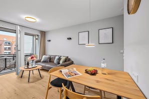 A modern living room with a sofa, a dining table, and a balcony. - Haus Elisabeth, Apartment 7, on the beach, with an underground parking space, Wi-Fi, and a balcony (Sylt)
