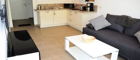 A compact living space with a kitchenette, a sofa, and a coffee table.
