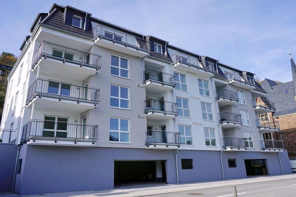 Ein mehrgeschossiges Wohngebäude mit Balkonen, einer Garage und blauem Himmel.