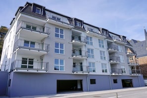 Ein mehrgeschossiges Wohngebäude mit Balkonen, einer Garage und blauem Himmel.