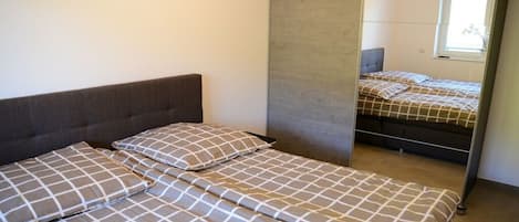 Un dormitorio con dos camas, un espejo grande y una ventana.
