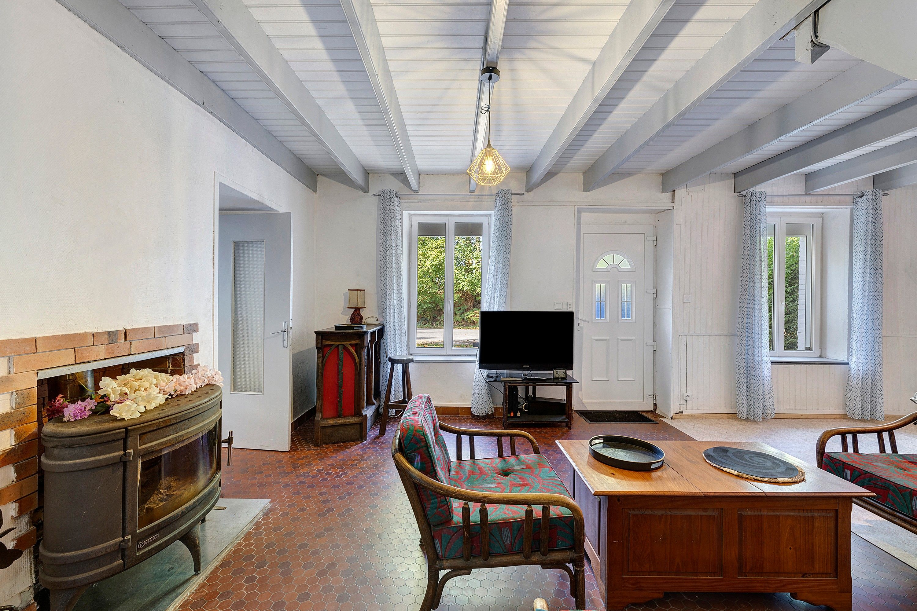 Een woonkamer met een open haard, een televisie en een eethoek met stoelen en een tafel.