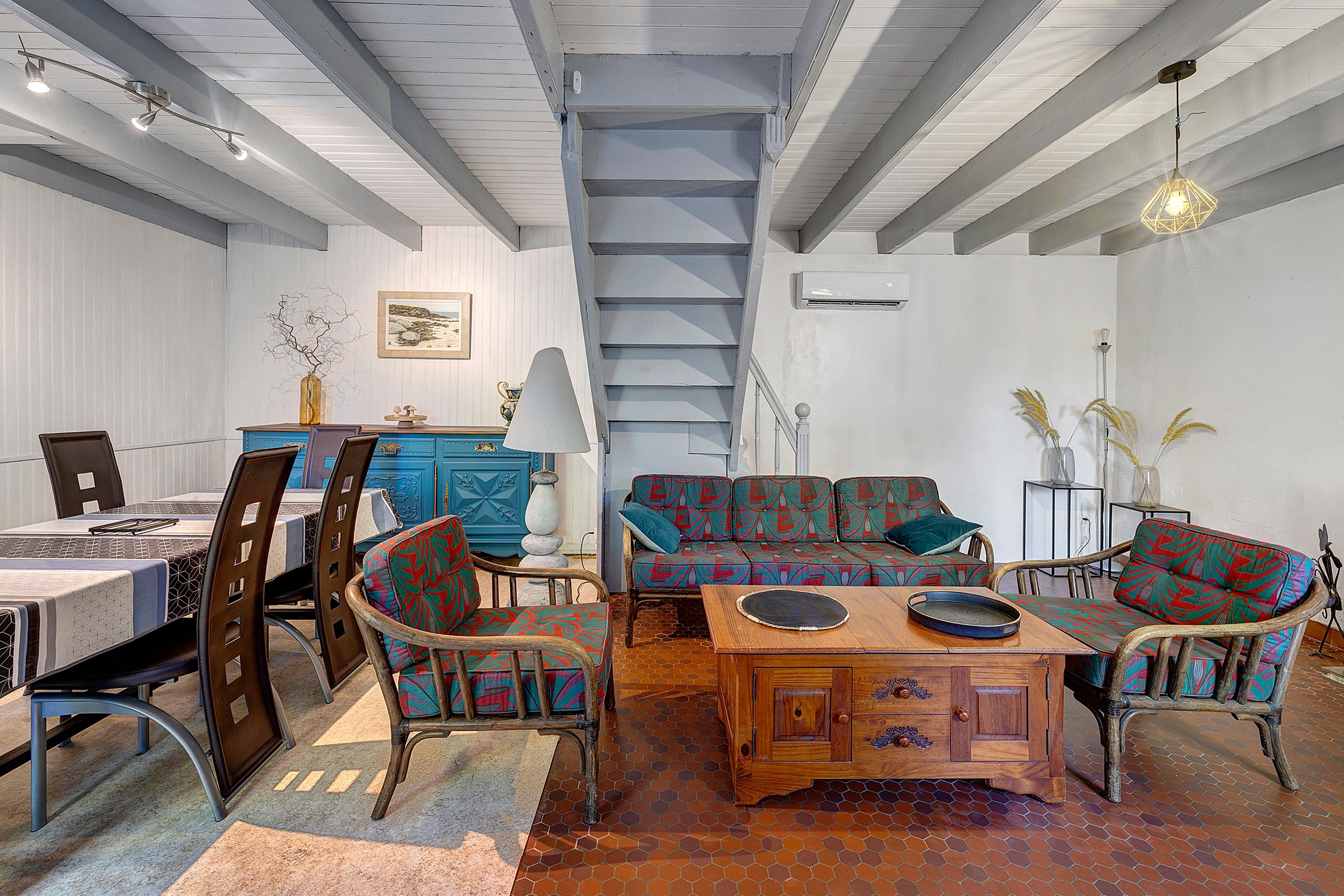 Una habitación amplia con zona de comedor, un conjunto de sofás y una escalera.