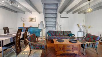 Una habitación amplia con zona de comedor, un conjunto de sofás y una escalera.