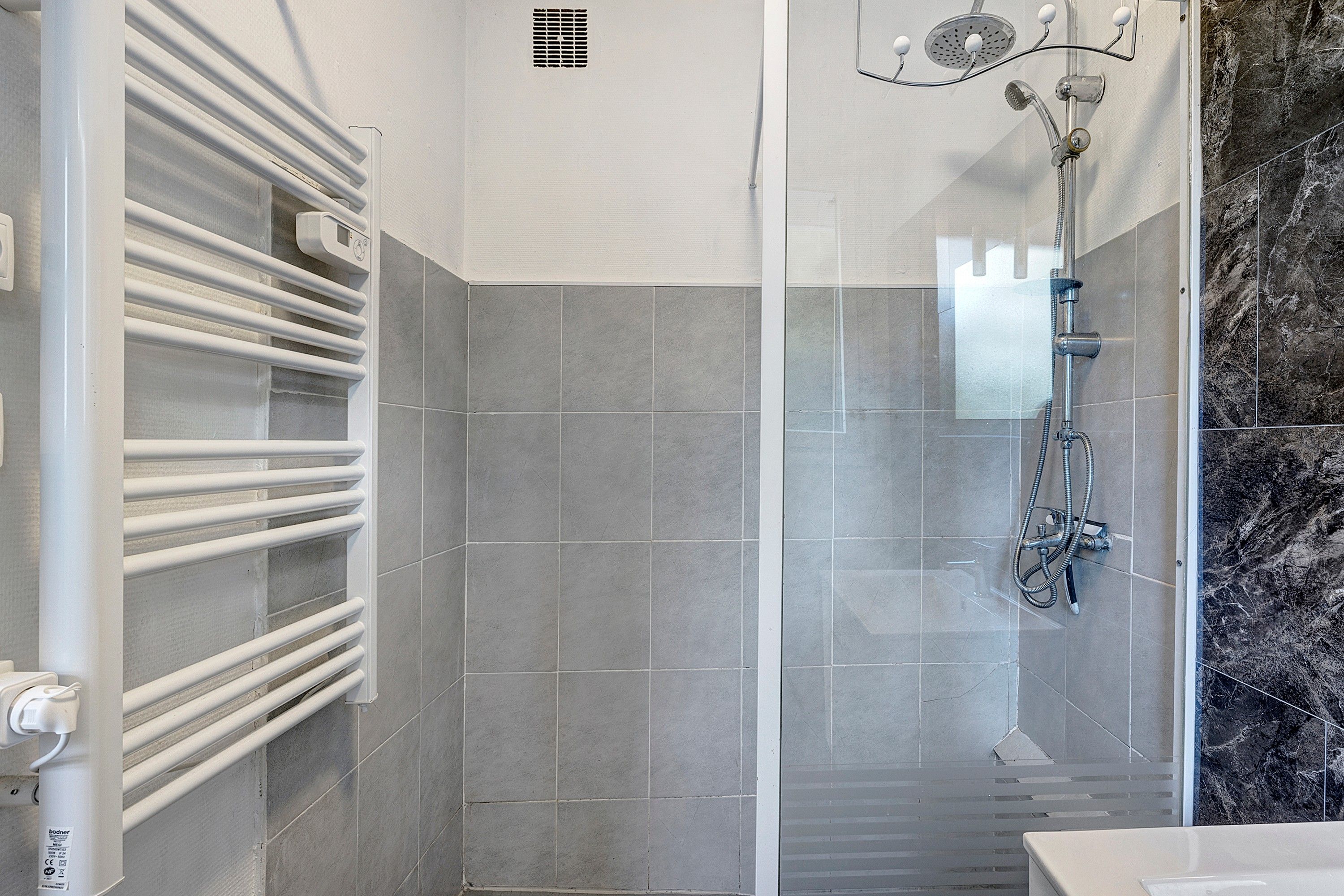Un bagno moderno con doccia, asciugamano e parete in marmo.