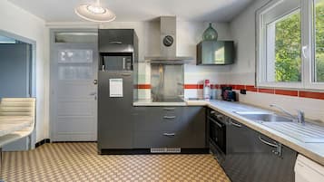 A compact kitchen with a built-in microwave, oven, and a window with a view of greenery.