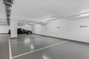 A parking garage with marked parking spaces, a car parked inside, and directional signs. - Haus Elisabeth, Apartment 11, on the beach, with an underground parking space, Wi-Fi, and a balcony (Sylt)