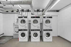 A laundry facility with multiple Siemens branded washing machines, ventilation ducts, and a tiled floor. - Haus Elisabeth, Apartment 11, on the beach, with an underground parking space, Wi-Fi, and a balcony (Sylt)