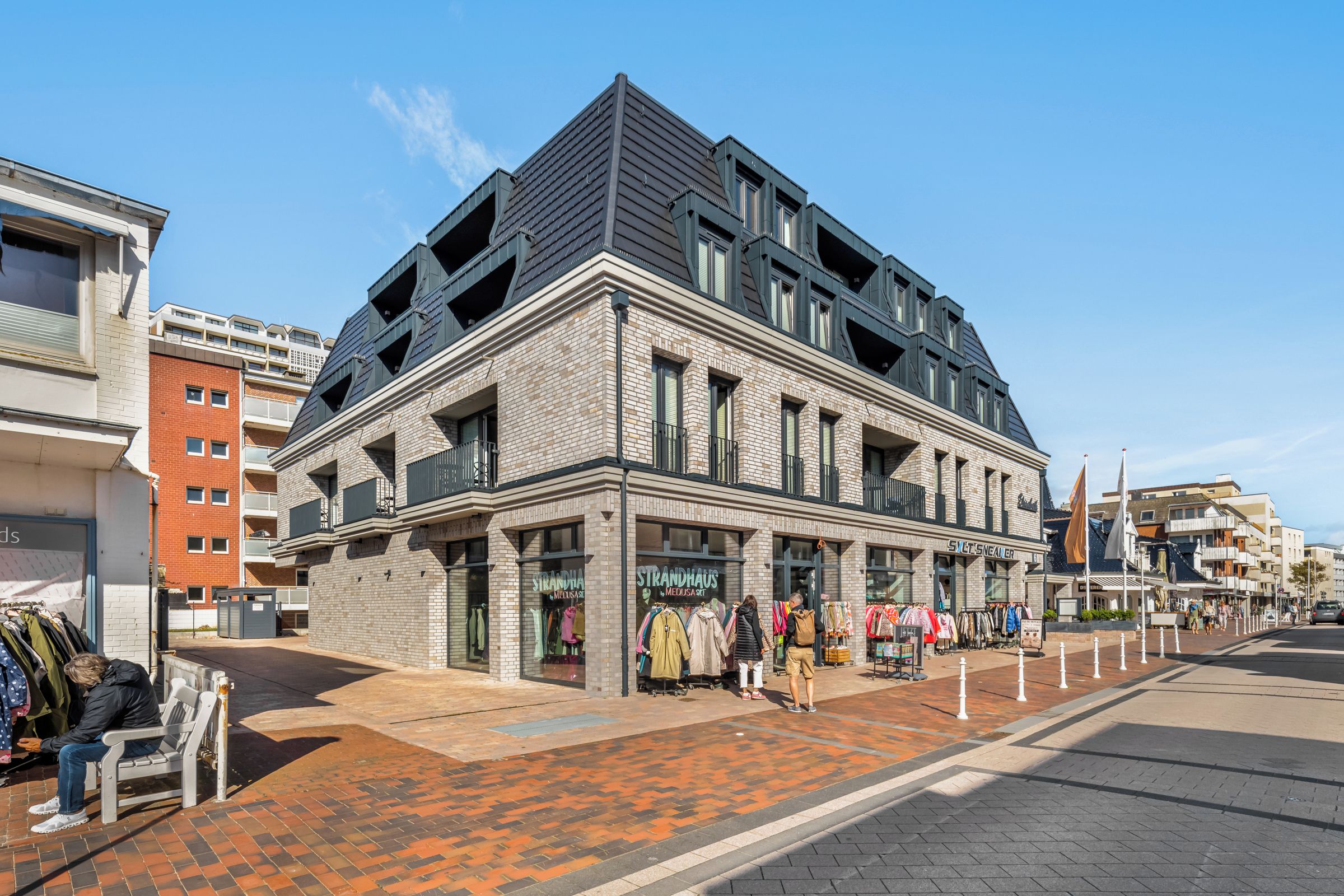 Un bâtiment moderne avec une façade en briques, de nombreuses fenêtres et un toit plat.
