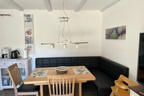 Ein Essbereich mit Holztisch, schwarzem gepolsterten Bänken und einer hängenden Leuchte.