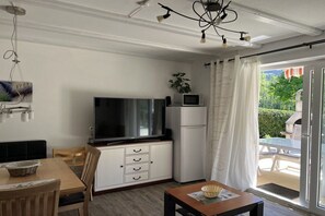 Ein kompakter Wohnbereich mit Flachbildfernseher, Mikrowelle und Essbereich mit Tisch und Stühlen.
