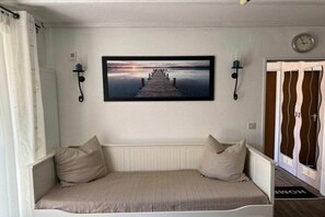 Ein Zimmer mit einem Bett, einem Wandbild von einem Steg, einer Uhr und einer Tür mit ungewöhnlichem Design.