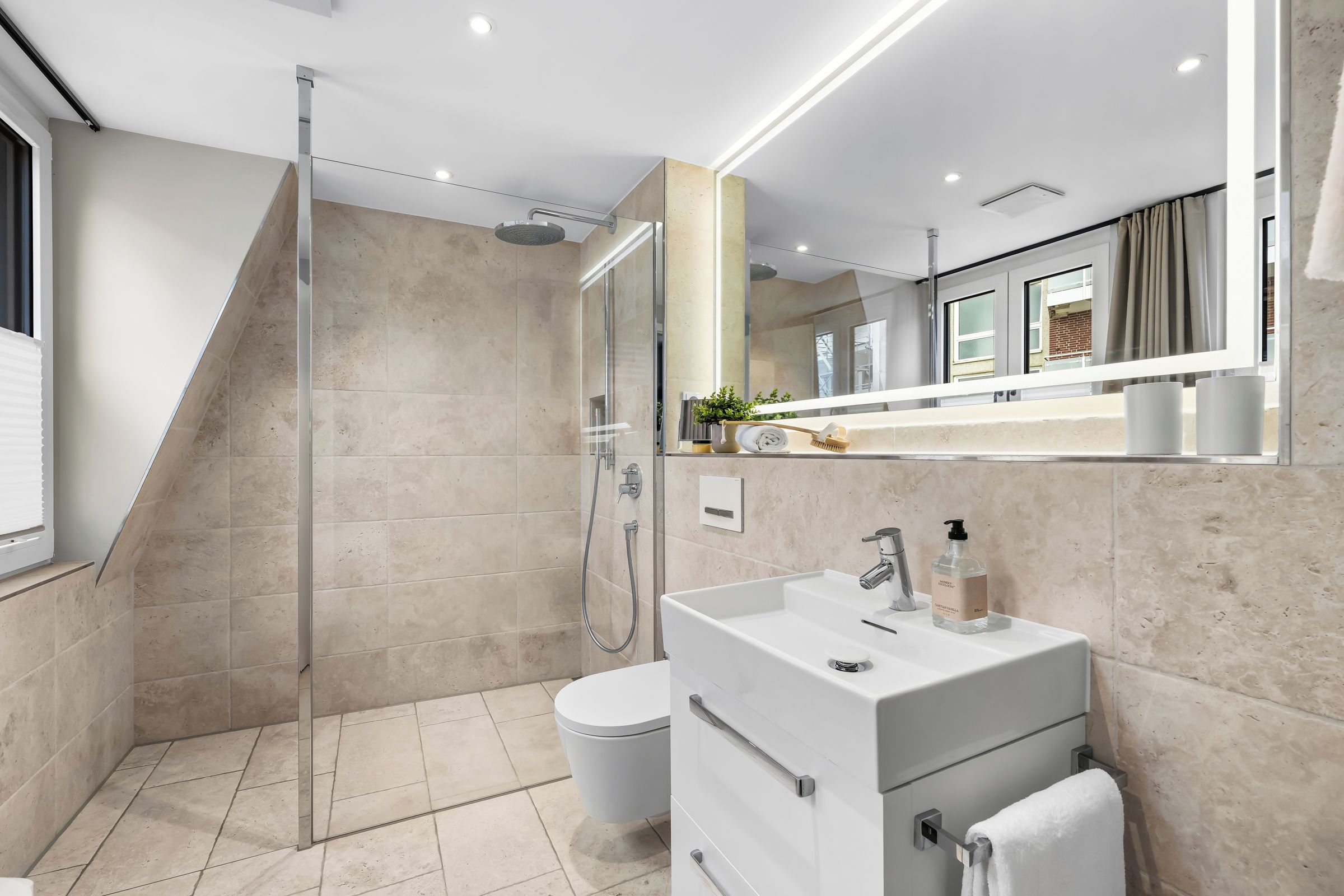 Une salle de bain moderne avec une douche à parois de verre, un meuble-lavabo blanc avec un miroir et des toilettes.