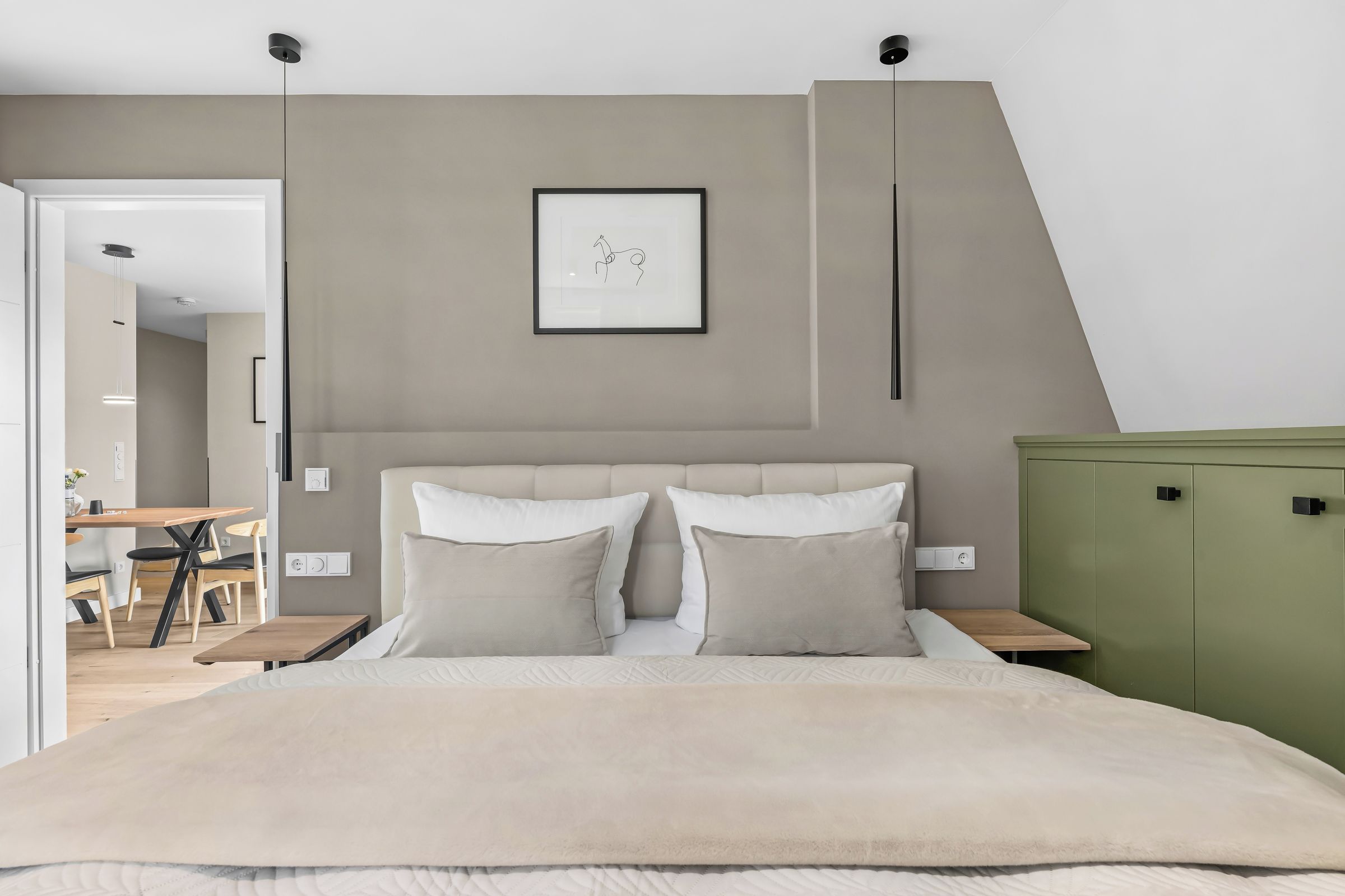 A bedroom with a bed, two bedside tables, a green cabinet, and a framed picture on the wall.