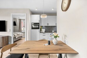 Eine moderne Küche mit weißen Schränken, einem Edelstahlbackofen und einem Essbereich mit Holztisch und Stühlen.