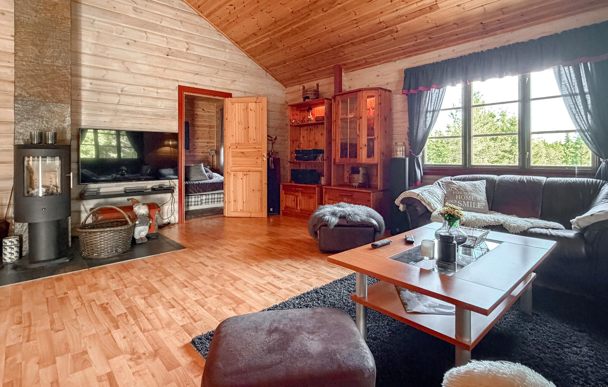 A cozy living room with a fireplace, wooden walls, a sofa, a coffee table, and a television.