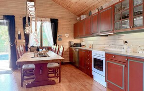 A wooden interior with a dining table, chairs, a kitchen with cabinets and appliances, and a view through the window. - 2 bedroom gorgeous home in årjäng (Årjäng)