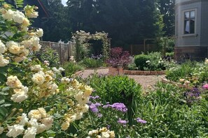 A garden with a wooden arbor, various flowering plants, and a brick pathway. - Villa Heimlicher Grund (Geratal \/ OT Gräfenroda)