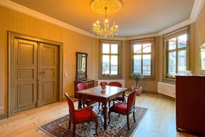 A dining room with a wooden table, red chairs, a chandelier, and large windows. - Villa Heimlicher Grund (Geratal \/ OT Gräfenroda)