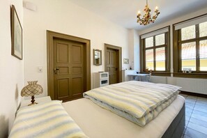 A bedroom with two beds, a chandelier, a window with a view, and a door. - Villa Heimlicher Grund (Geratal \/ OT Gräfenroda)