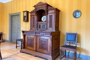 A wooden cabinet with intricate carvings, a clock, and a framed picture on a wall. - Villa Heimlicher Grund (Geratal \/ OT Gräfenroda)