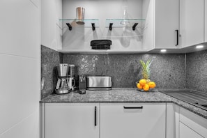 A modern kitchen with granite countertops, a coffee maker, a toaster, and a fruit bowl. - Haus Elisabeth, Apartment 13, on the beach, with underground parking, Wi-Fi, and a balcony (Sylt)