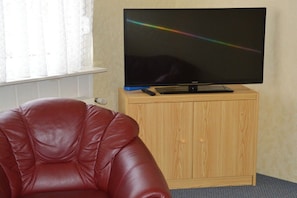 Habitació amb una cadira de pell, un armari de fusta i un televisor a la part superior.