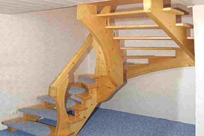 A wooden spiral staircase with a handrail and steps. - Holiday apartment with 3 bedrooms (Neuschoo)