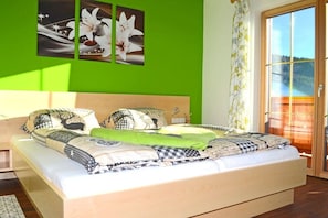 A bedroom with a bed, a green wall, and a window with a view. - Holiday apartment Longa (Weißpriach)