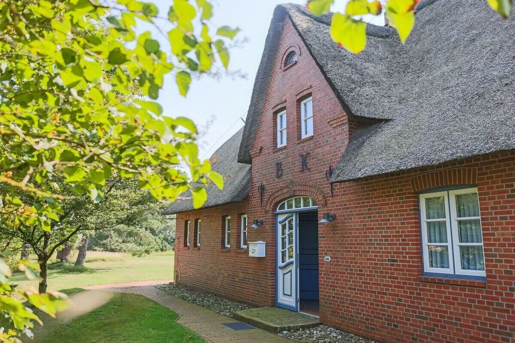A brick building with a steeply pitched roof, a front door, and a small porch area.