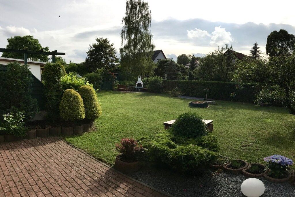 Un jardin bien entretenu, avec une pelouse, divers arbustes et un chemin en briques.