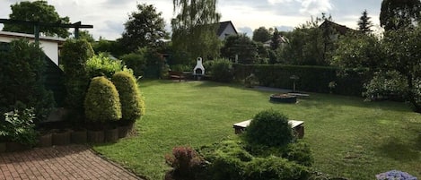 Un jardin bien entretenu, avec une pelouse, divers arbustes et un chemin en briques.