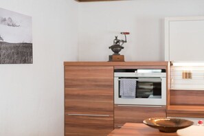 A kitchen with a built-in oven, wooden cabinetry, and a decorative item on top. - Edelweiss - Glacier Apartments (Flattach)