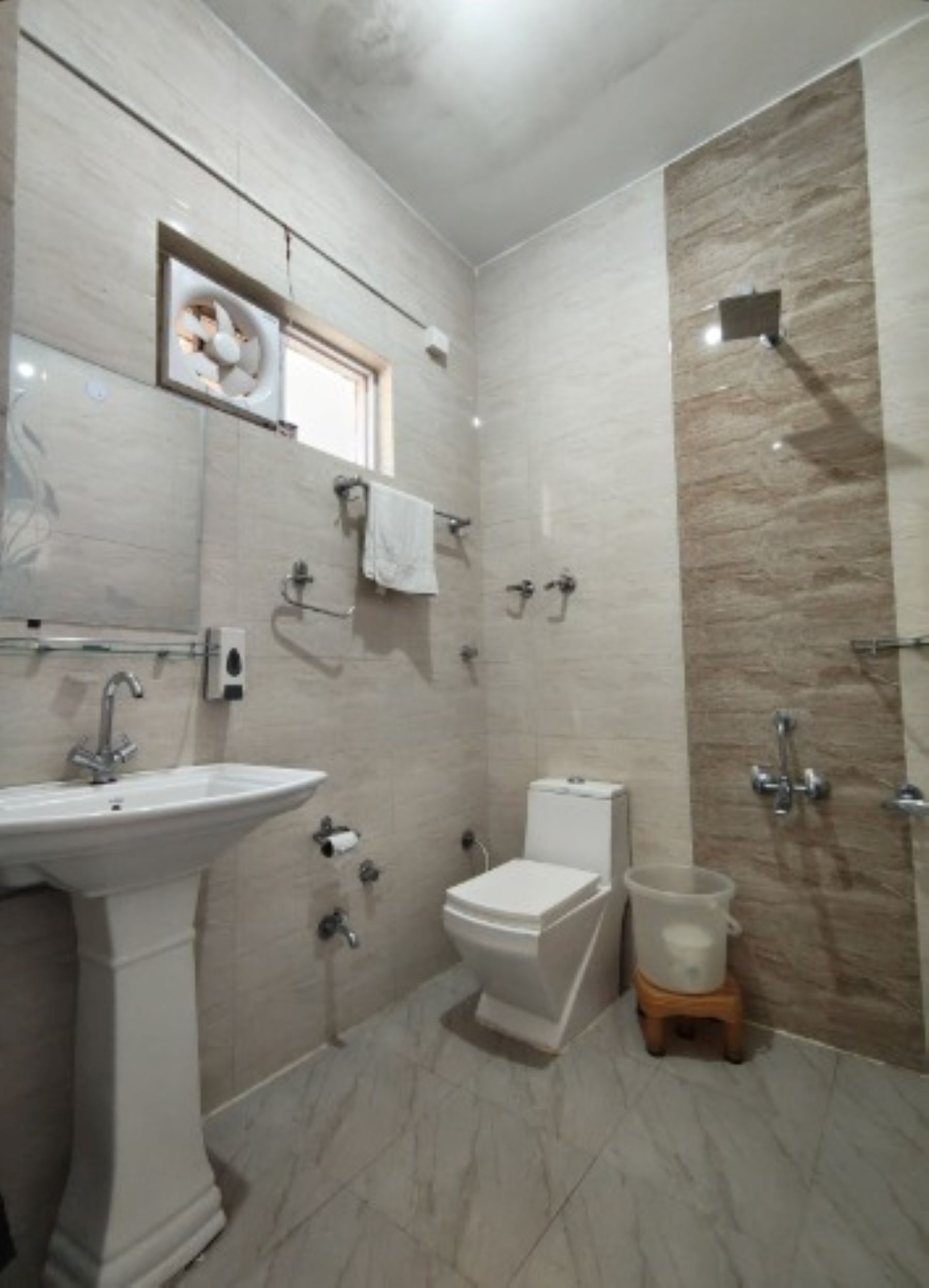 A bathroom with a pedestal sink, toilet, and shower area.