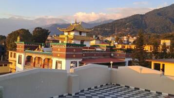 A traditional building with a multi-tiered roof, surrounded by a mountainous landscape.