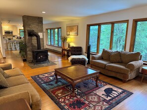 A cozy living room with a fireplace, a sofa, a coffee table, and a rug. - Luxury Chalet on 1.5 Acres: Mountain Views, Hot Tub, Gym, fire pit & Ping-Pong (Windham)
